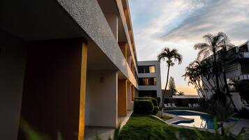 Un edificio moderno con piscina, palmeras y cielo despejado.