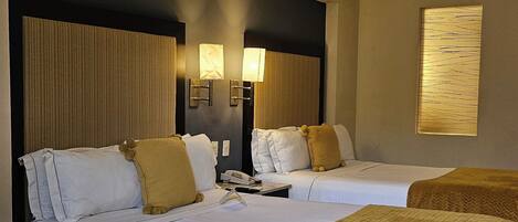 Une chambre d’hôtel avec deux lits, un canapé, un téléphone et une lampe fixée au mur.