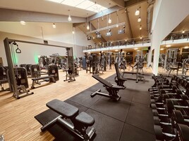 A spacious gym with various exercise equipment, including benches, dumbbells, and weight machines.