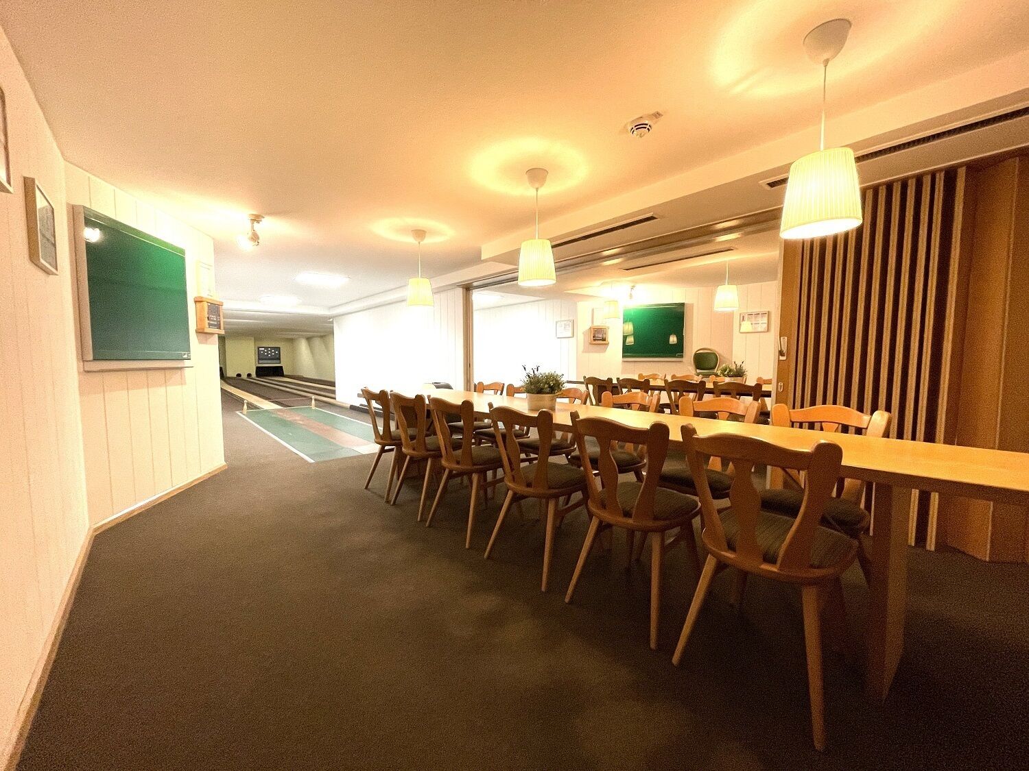 Un salón de conferencias con una larga mesa y sillas, una pizarra y una televisión.