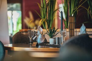 A dining table set with wine glasses, a candle, and a small plant.
