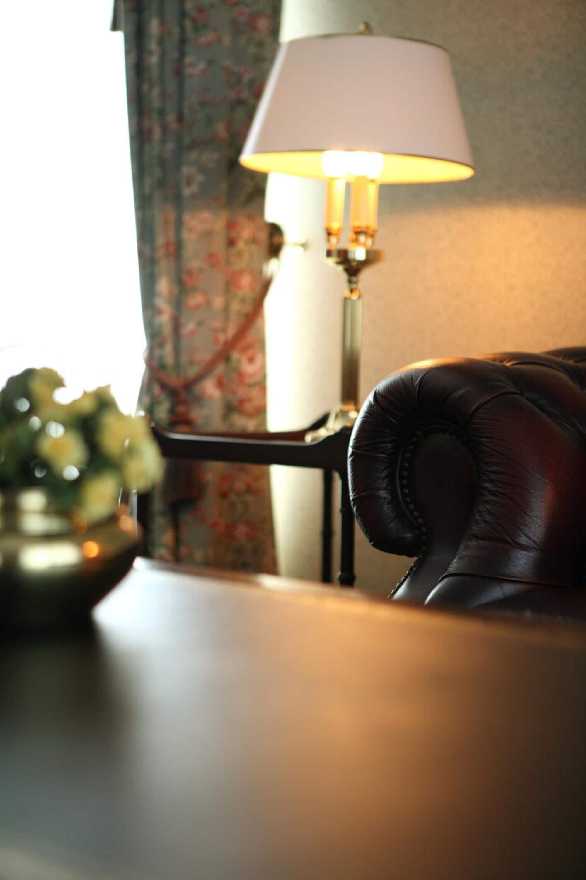A leather armchair, a lamp, and a vase with flowers on a table.