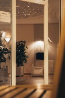 A modern interior with a seating area, a potted plant, and a wall-mounted TV.
