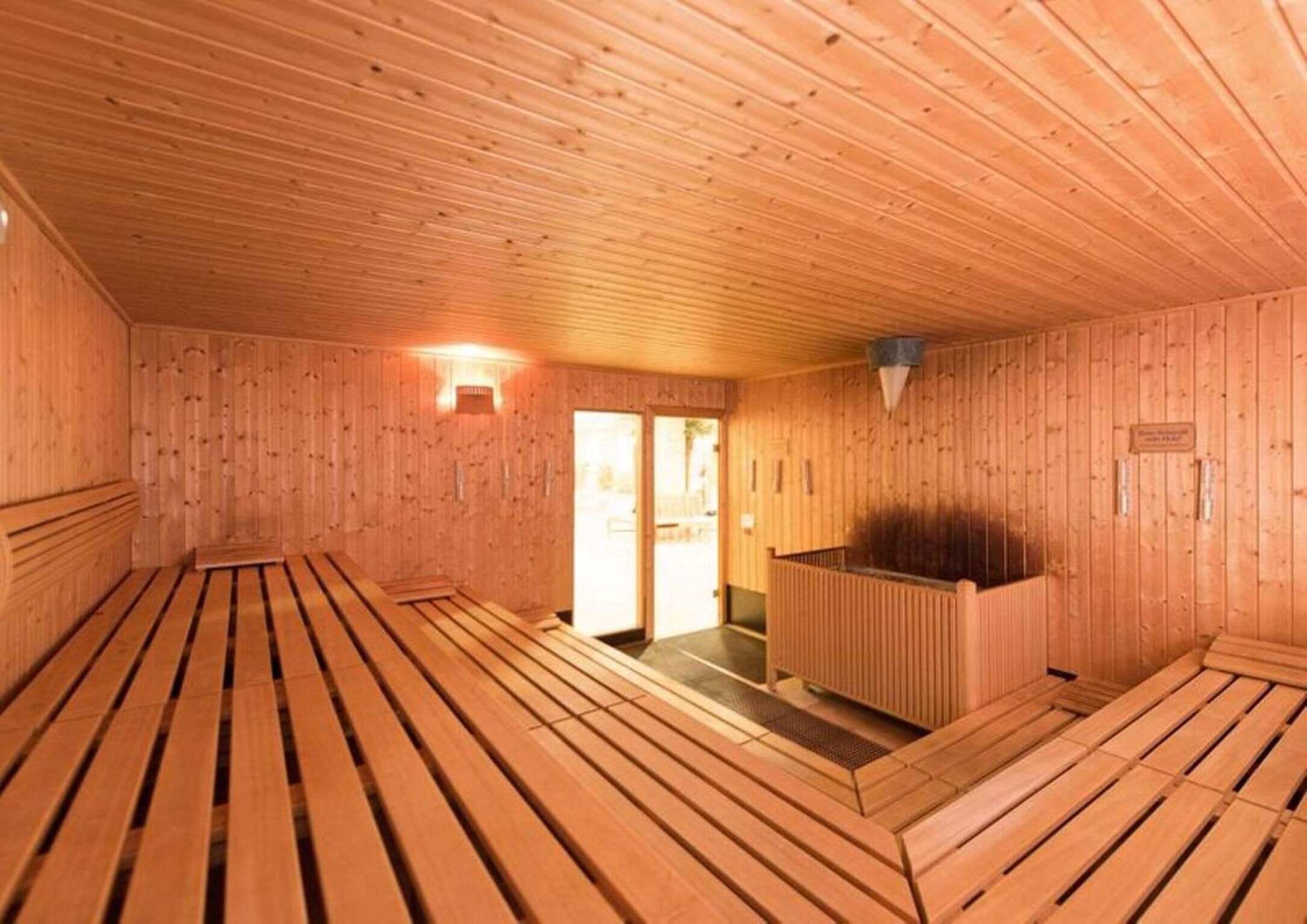 A sauna room with wooden benches and a bench in the center.