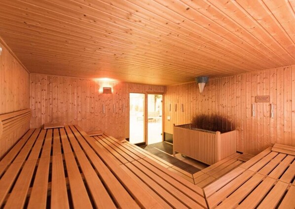Un sauna avec des bancs en bois et un banc au centre.