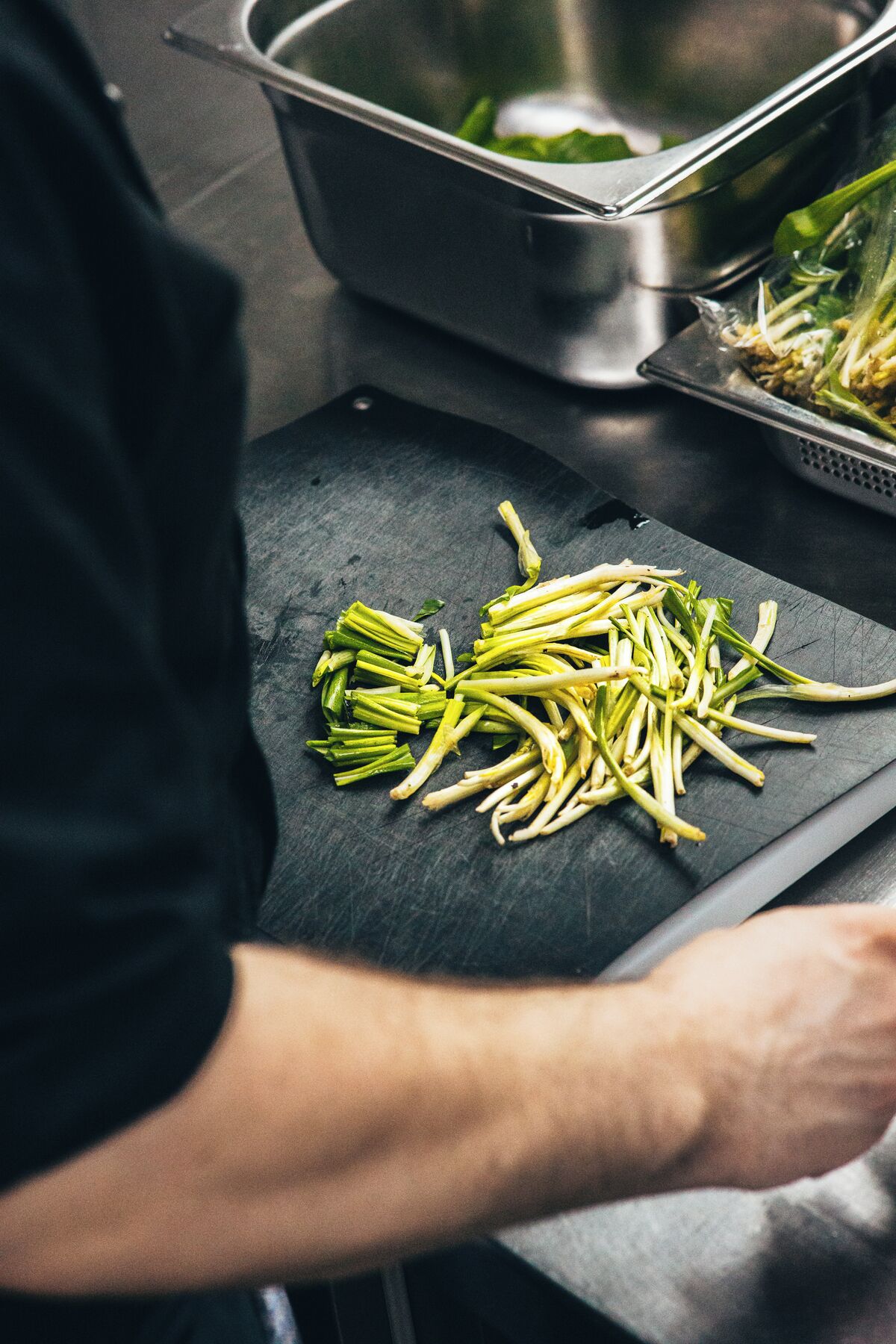 Una persona preparando comida en una tabla de cortar con verduras.