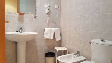 A bathroom with a sink, bidet, toilet, and a hairdryer on the wall.