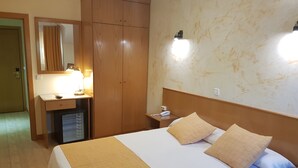 Ein Hotelzimmer mit Bett, Schreibtisch, Kleiderschrank und Spiegel.