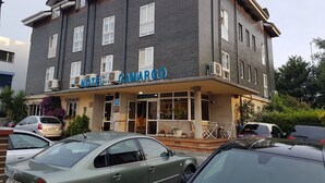 Ein mehrstöckiges Hotel mit dunkler Backsteinfassade, Klimaanlagen und einem Schild mit der Aufschrift "HOTEL CAMARGO".