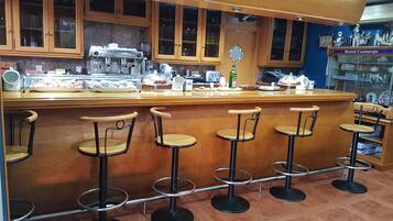 Zona de bar con taburetes de madera y una barra con diversos objetos.