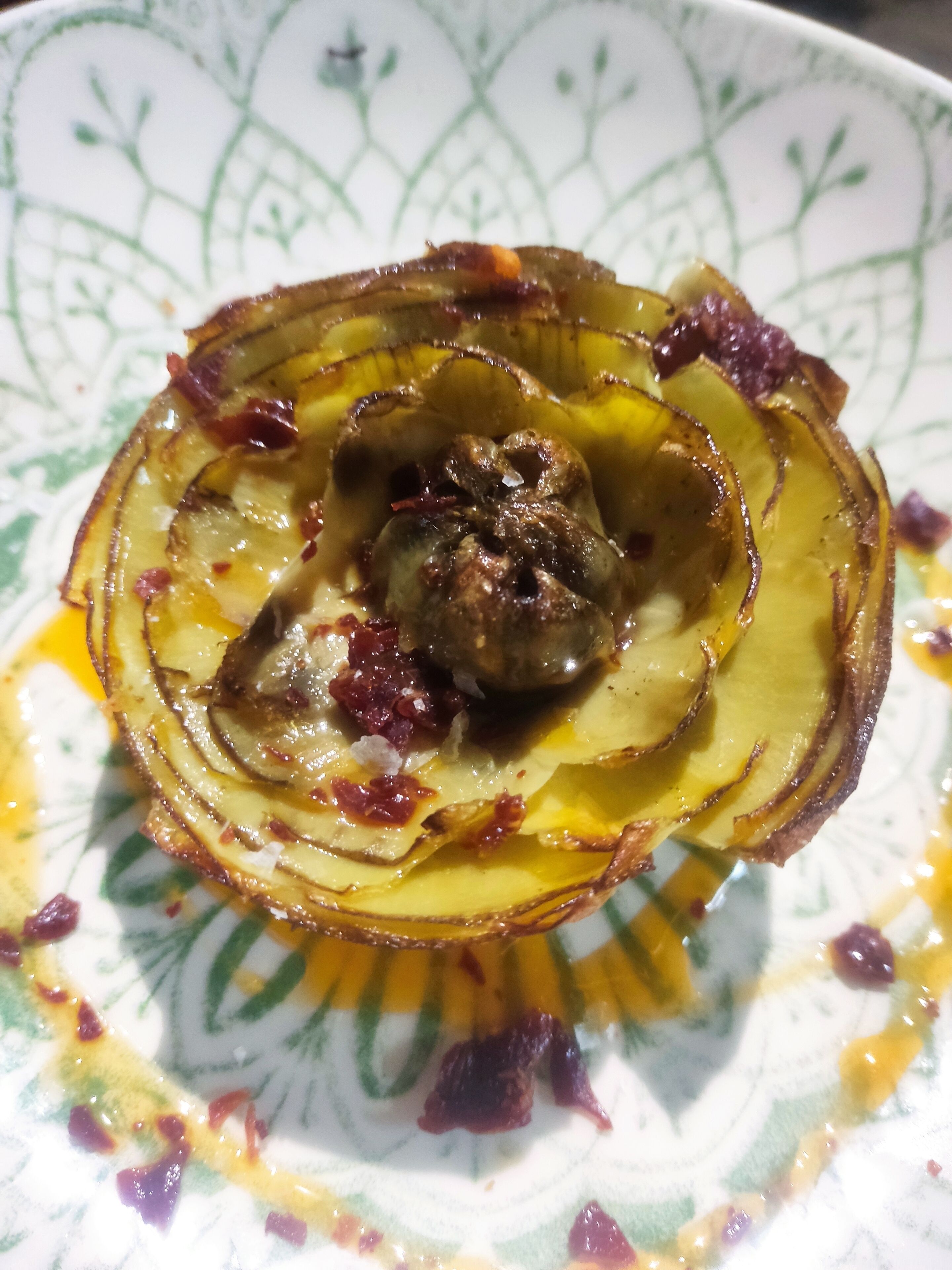 Un plato con un alimento, posiblemente un vegetal relleno, sobre un plato estampado.