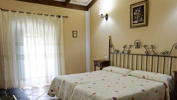 Un dormitorio con dos camas, una mesita de noche, una lámpara y un cuadro en la pared.