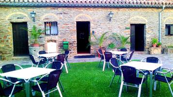 Un patio al aire libre con muros de piedra, techo de tejas y mobiliario exterior.