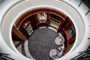 Vista circular de un vestíbulo con una mesa redonda y sillas, paneles de madera y una recepción.
