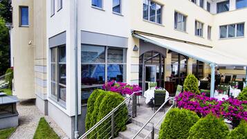 A modern hotel with a covered outdoor seating area, neatly arranged steps, and well-maintained landscaping.