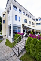 Un hotel moderno con una zona de estar al aire libre cubierta, escalones ordenados y jardines bien cuidados.