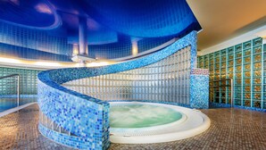 A large indoor swimming pool with a curved design, surrounded by blue-tiled walls and floor. - Hotel Haffner Resort & SPA - Destigo Hotels (Sopot)