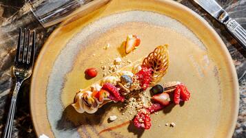 Un dessert présenté sur une assiette, accompagné d’une serviette et de couverts, le tout posé sur une surface en marbre.