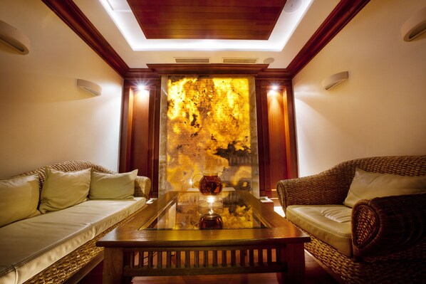 A room with a glass coffee table, two sofas, and a decorative wall with a textured pattern.