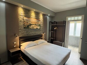 A modern bedroom with a large bed, a stone wall mural, a wooden wardrobe, and a view of the outdoors. - Hotel Perugino (Milan)