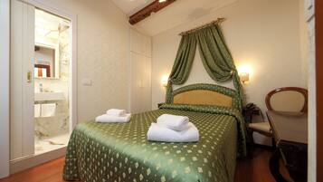 A hotel room with a bed, a chair, a table, a mirror, and a bathroom visible through an open door.