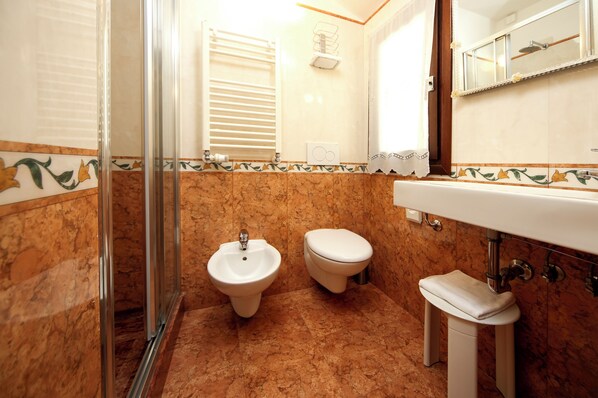 Un baño con bidé, inodoro y lavamanos.