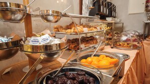 Un bufé con diversos alimentos, entre ellos frutas, pasteles y salsas.