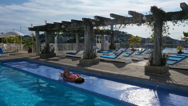 Piscina con sillones de descanso y una estructura de pérgola.