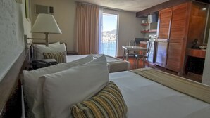 Habitación de hotel con cama, escritorio, silla, ventana con cortinas y vistas al exterior.