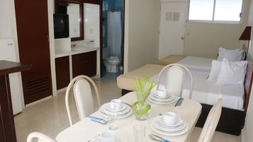 A hotel room with a dining area, a bed, a bathroom, and a TV.