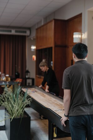 A person standing at a counter in a room with wooden cabinets and a potted plant.