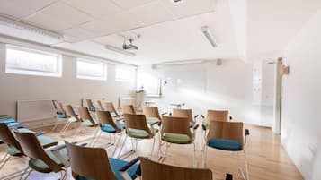 A conference room with rows of chairs, a whiteboard, and a projector.