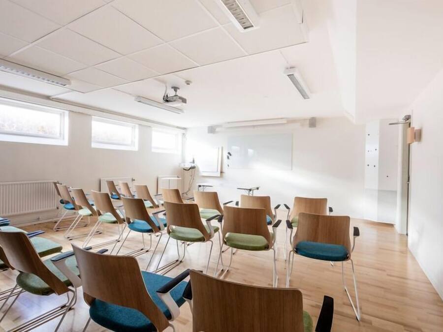A conference room with rows of chairs, a whiteboard, and a projector.