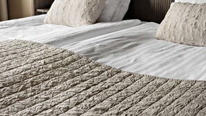 A neatly made bed with a textured blanket and two pillows.