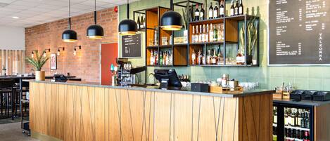 A bar area with a wooden counter, shelves with bottles, and a menu on the wall.