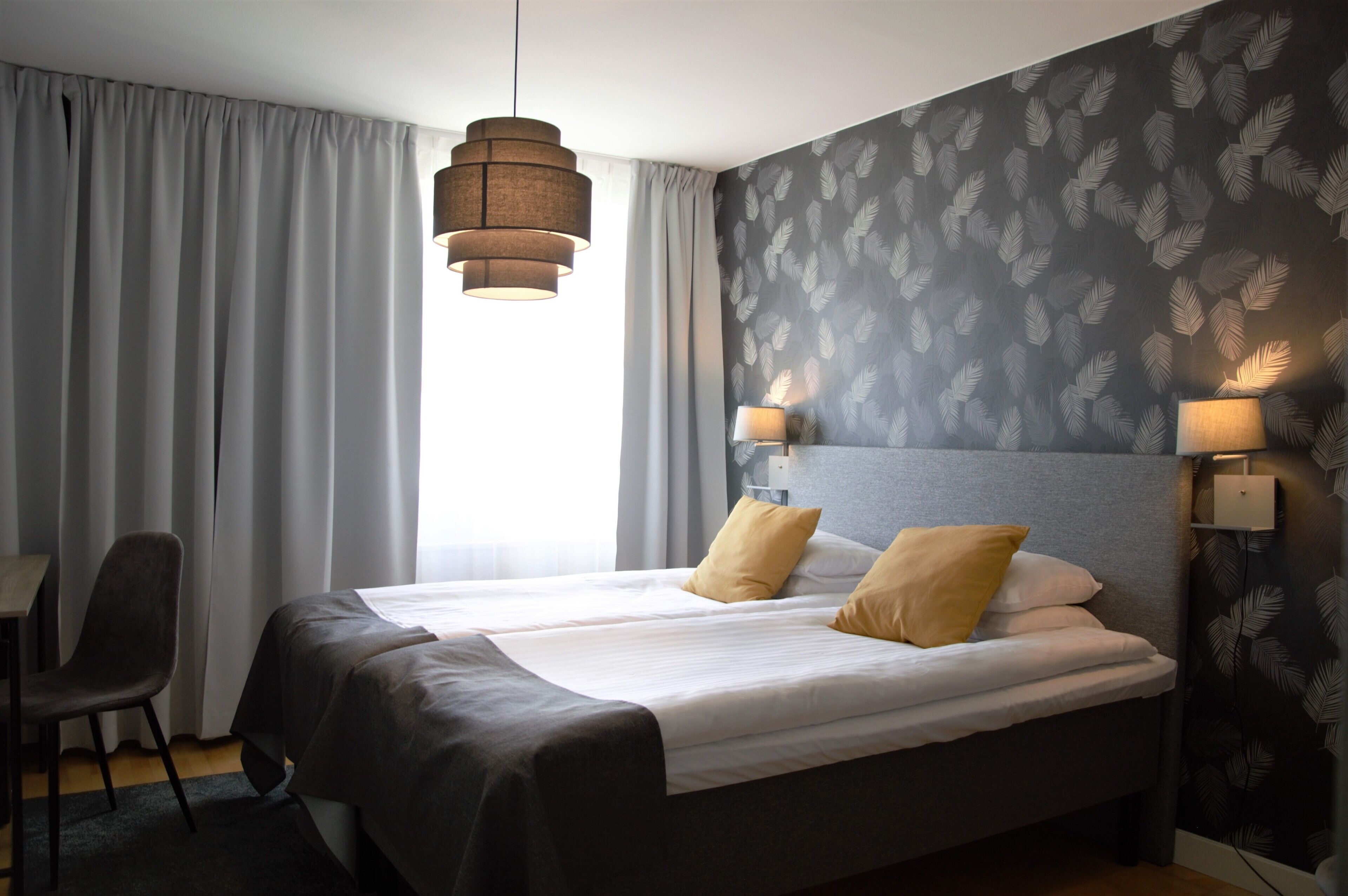 Une chambre d’hôtel avec un lit, deux lampes de chevet, un bureau et une chaise.