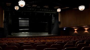 Un auditorio con hileras de asientos, un escenario y candelabros.