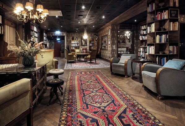 Una biblioteca acogedora con estanterías de madera, una alfombra grande y asientos cómodos.