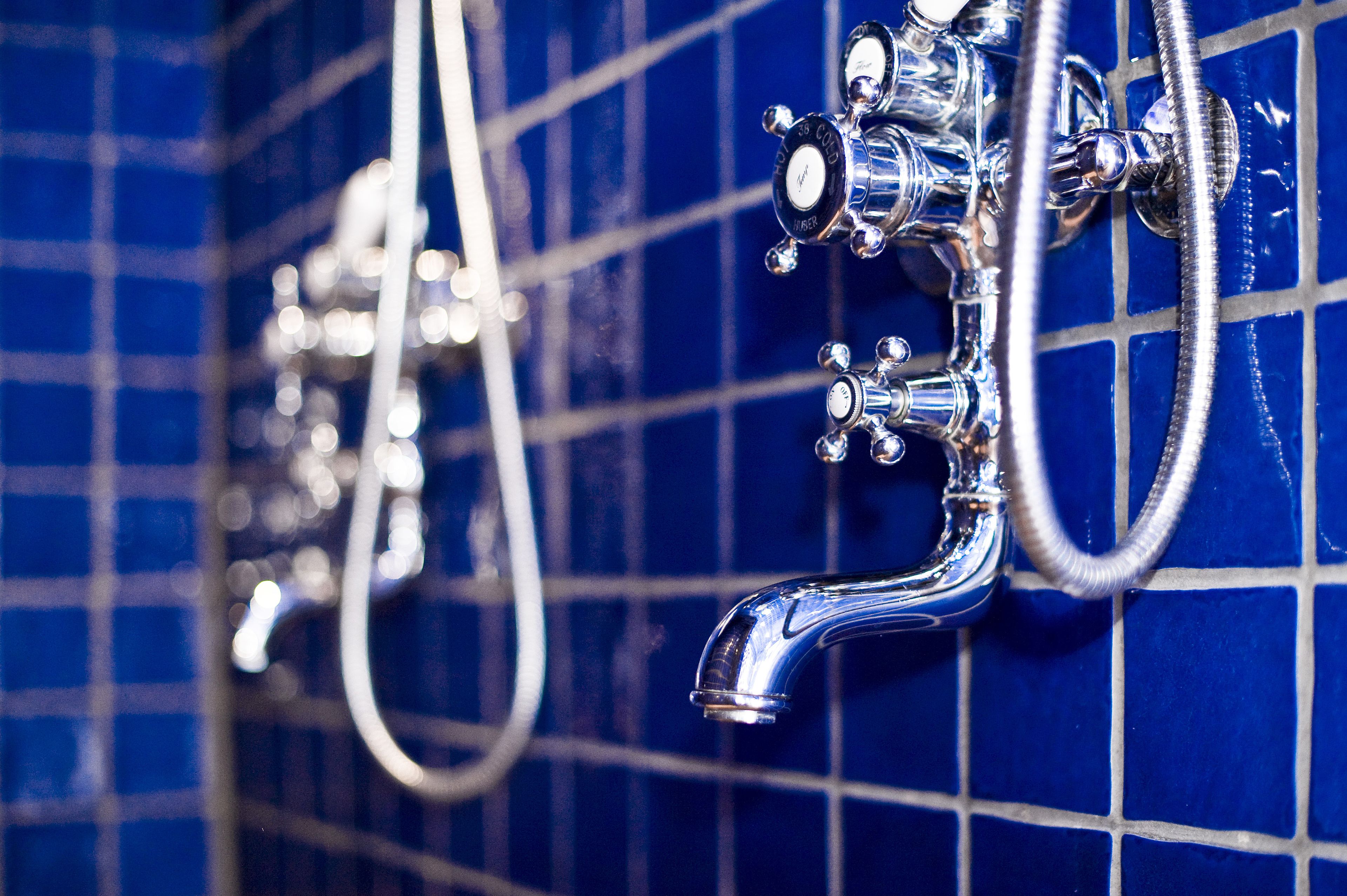 A bathroom with blue tiled walls and chrome fixtures.