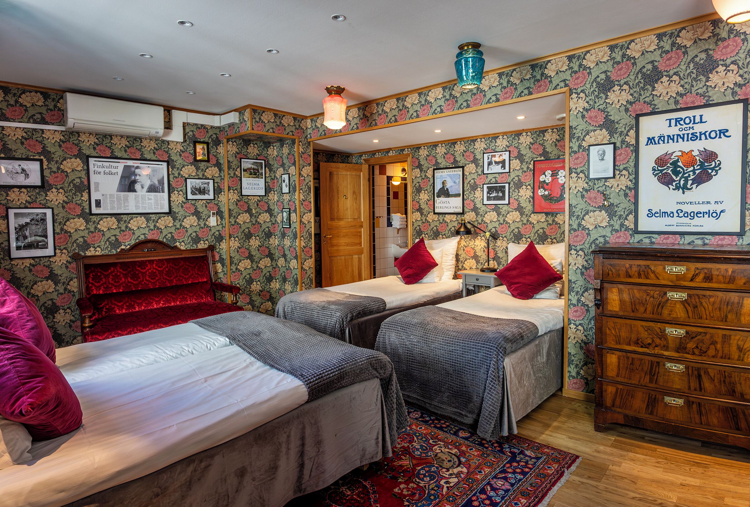 A room with two beds, a dresser, and a mirror.