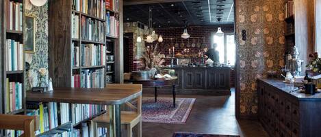 A cozy library with bookshelves, a wooden table, and a patterned rug.