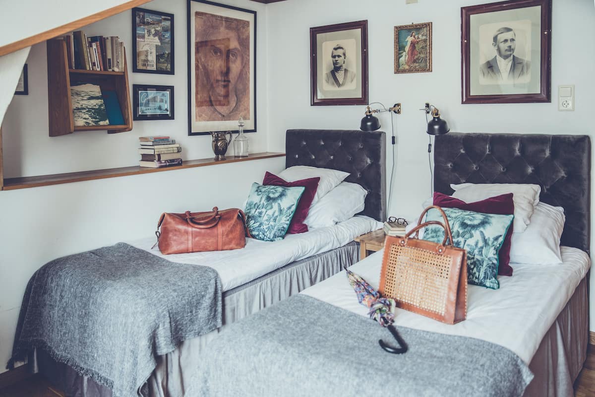 Ein Schlafzimmer mit zwei Betten, einem Bücherregal und gerahmten Bildern an der Wand.
