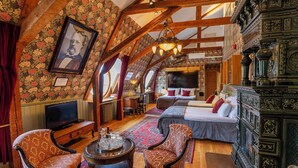 Una habitación con cama, dos sillas, televisor y techo de madera.