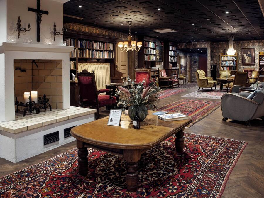 Une bibliothèque avec des étagères, une cheminée et un lustre.