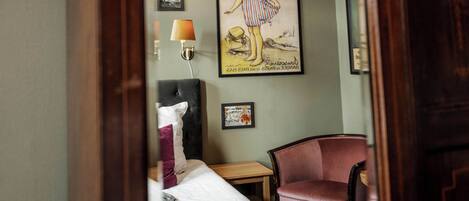 Una habitación de hotel con una cama, una silla, una lámpara y un cuadro en la pared.