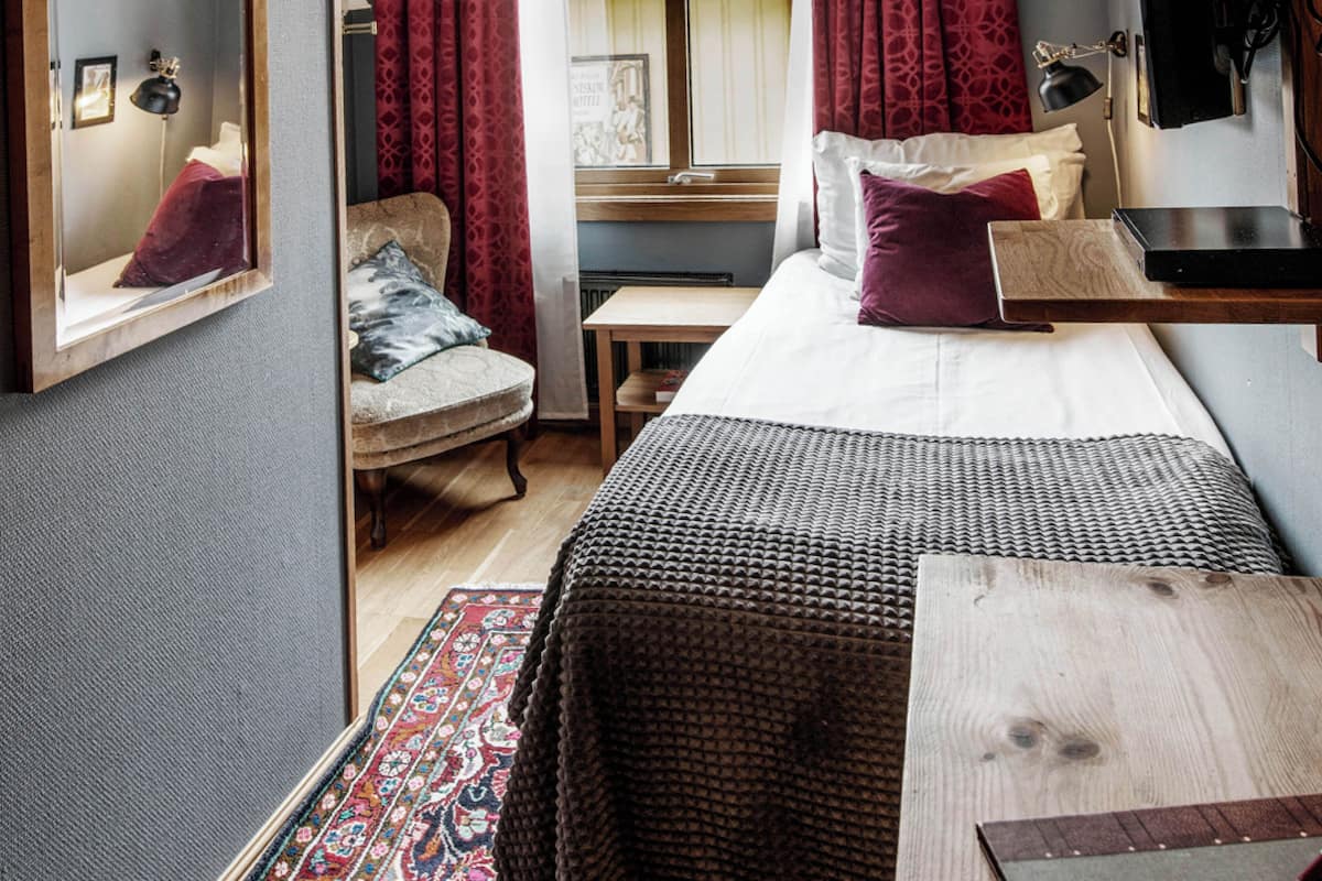 Ein gemütliches Schlafzimmer mit einem Bett, einem Sessel, einem kleinen Tisch und einem Spiegel.