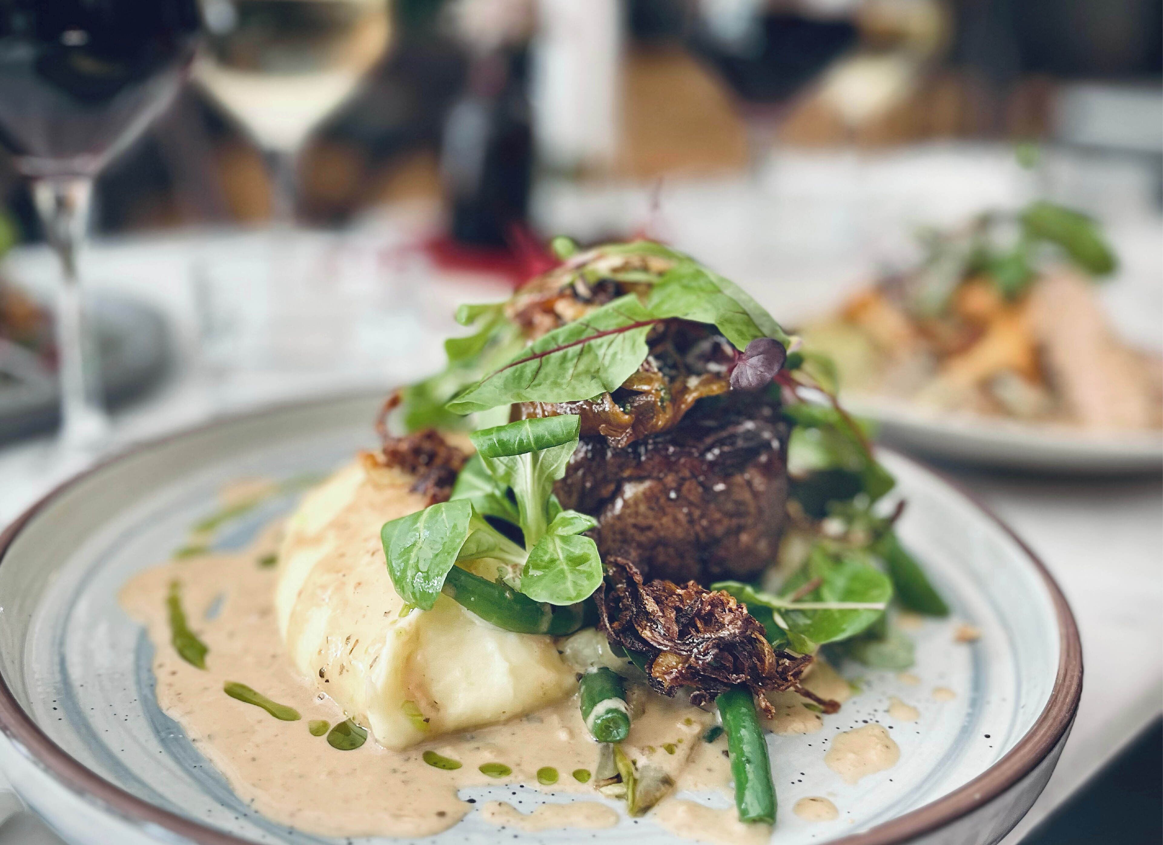 Prato de comida com molho cremoso, vegetais verdes e acompanhamentos crocantes.