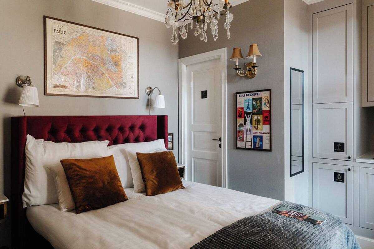 Ein Hotelzimmer mit einem großen Bett, einer Chandelüster, einer Karte von Paris und einer Pinwand.