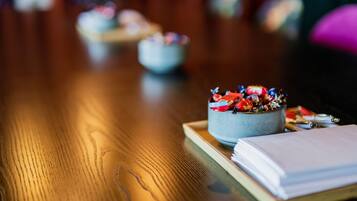 A wooden table with a bowl of colorful candies, a notebook, and pens.