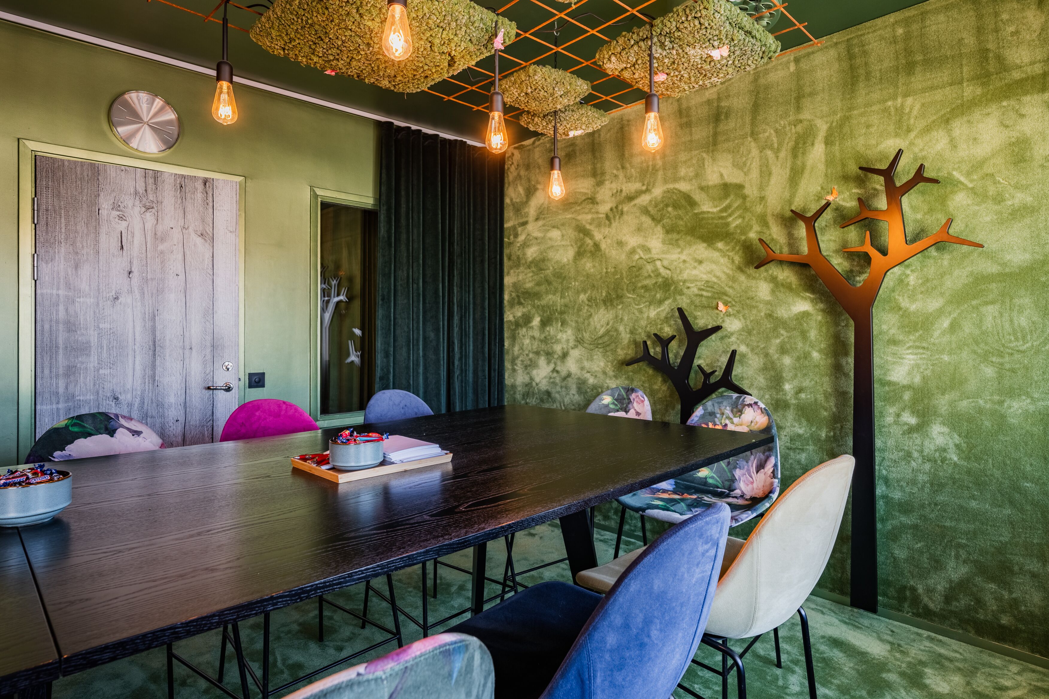 A conference room with a long table, chairs, and a decorative tree on the wall.